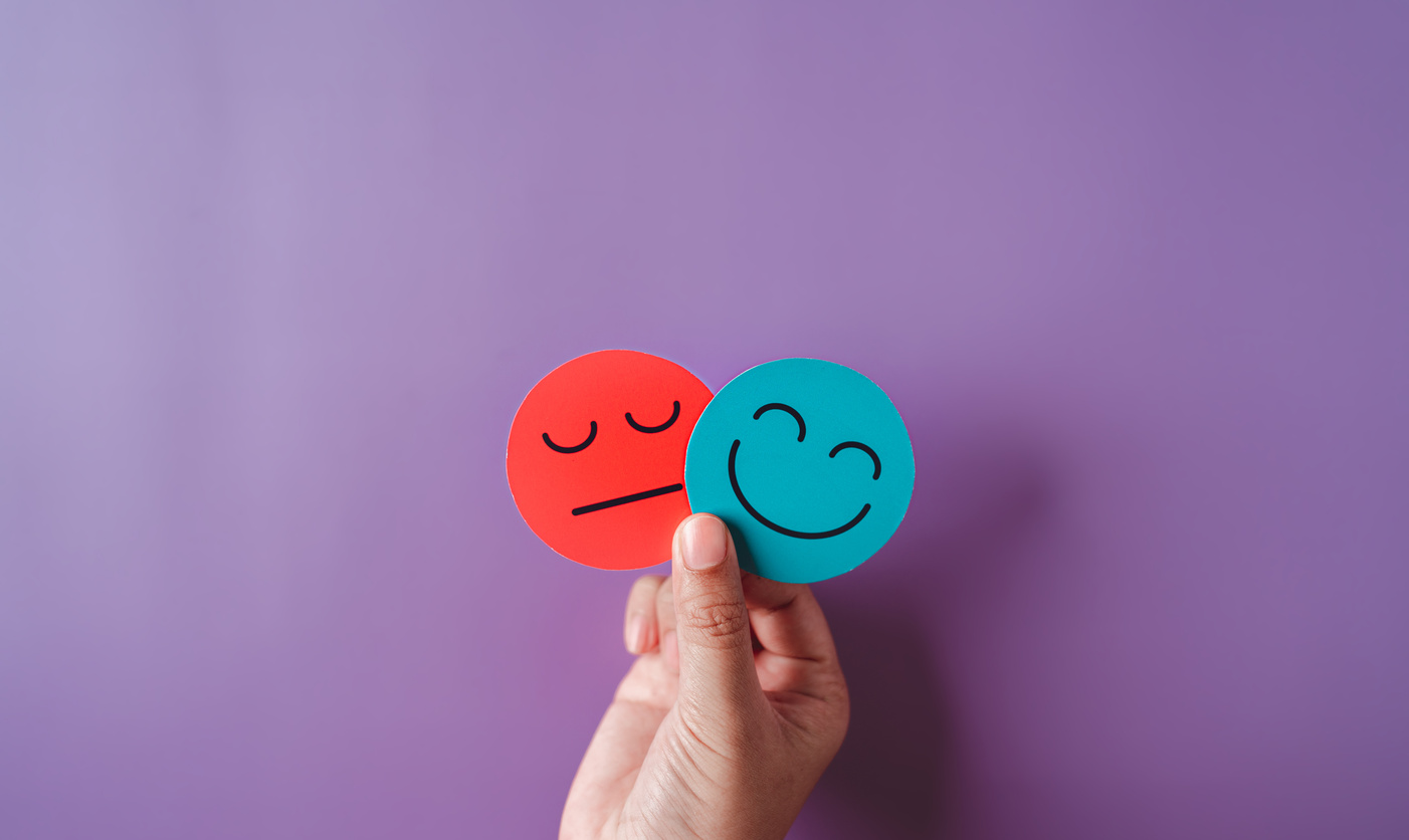 Hands holding sad face hiding or behind happy smiley face, bipol